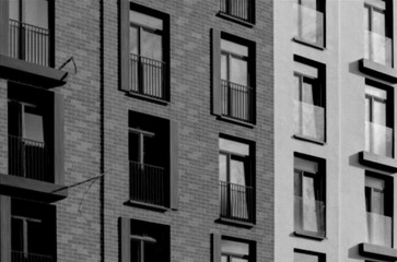 Black and white close-up of a modern residential facade with repeating brick and concrete surfaces,