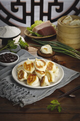 Pan-Fried Chinese Dumplings on Dark Wooden Table - Traditional Xuzhou Delicacies Scene