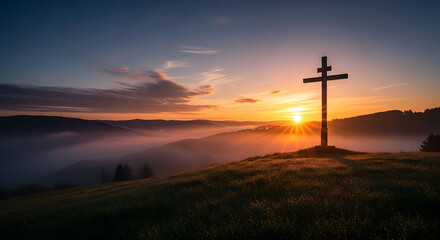 A wooden cross stands silhouetted on a grassy hilltop against a vibrant sunrise, with fog nestled in the valleys below.