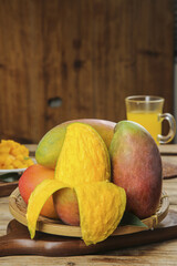 Fresh Hainan Guifei Sweetheart Mangoes in Basket with Tropical Fruit Juice on Rustic Wood Table