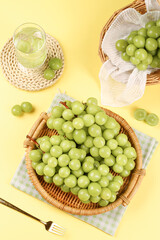 Fresh Green Grapes in Wicker Baskets with Sparkling Juice on Yellow Background