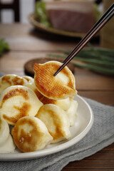 Panfried Golden Dumplings with Chopsticks on Wooden Table Asian Cuisine Delicacies