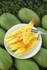 Freshly Picked Green Hainan Mangoes Sliced with Chili Seasoning on White Plate