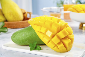 Fresh Hainan Mango with Green Skin and Golden Jinhuang Flesh Cut in Cubes on White Marble Counter
