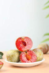 Fresh Red Plum Fruit Halves on White Plate with Natural Background