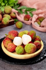 Fresh Hainan Litchi Fruits in Wooden Bowl - Tropical Asian Delicacy with Peeled White Flesh on Dark Slate Background
