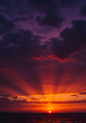 Obraz premium Dramatic Sunset Over Ocean Radiant Sunbeams, Fiery Sky, Cloudscape, Nature's Beauty, Evening Glow.