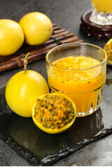 Fresh Golden Passion Fruit Juice with Whole and Halved Fruits on Dark Slate Board - Healthy Tropical Drink