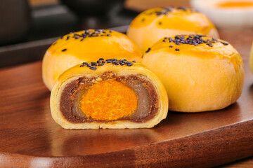 Golden Egg Yolk Mooncakes with Red Bean Paste and Black Sesame Seeds on Wooden Board