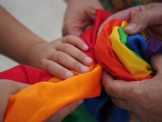 Fototapeta premium Realistic photo of hands holding vibrant rainbow pride flag against clean background symbolizing diversity inclusion acceptance love, Selective Focus