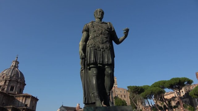 Low-angle orbiting shot of the bronze statue of Julius Caesar at the Imperial Forums in Rome, Italy.
