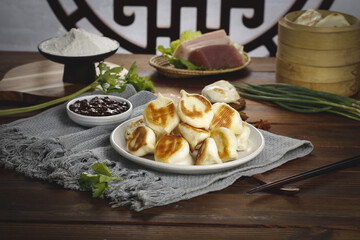 Traditional Chinese Pan-Fried Dumplings with Golden Base and Dark Sauce on Wooden Table
