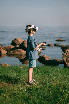Child wearing gamer glasses plays on seashore