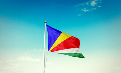 Seychelles flag waving in blue sky with mast.