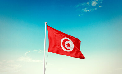 Tunisia flag waving in blue sky with mast.