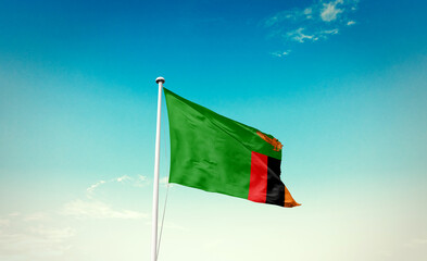 Zambia flag waving in blue sky with mast.