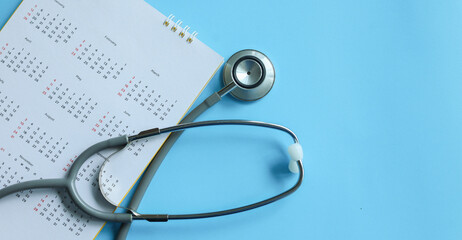 close up top view on stethoscope on calendar with over blue background for design about ads or banner of doctor appointment and health checkup following personal lifestyle concept