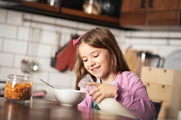 Smiling playfully little girl makes breakfast for herself.