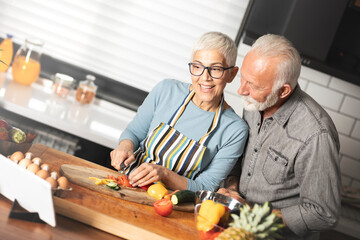Senior couple reading food blog on digital tablet cooking