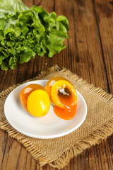 Golden Salted Duck Eggs with Orange Yolks and Fresh Lettuce on Wooden Table
