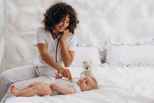 Check up routine. Using stethoscope. Female doctor is with newborn baby indoors