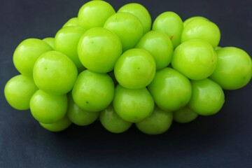 Fresh Shine Muscat or Vitis grapes close up, isolated on dark background.