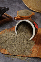 Organic Small Green Mung Beans Spilling from Traditional Bowl on Bamboo Mat for Healthy Asian Cooking