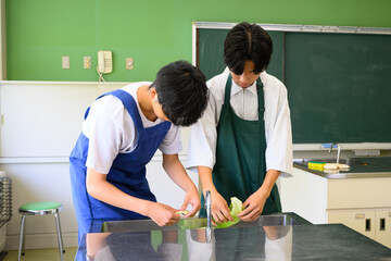 料理教室で学ぶ男子学生　二人で楽しくクッキングするシーン