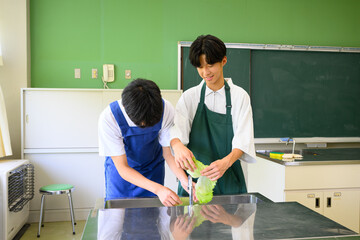 料理教室で学ぶ男子学生　二人で楽しくクッキングするシーン