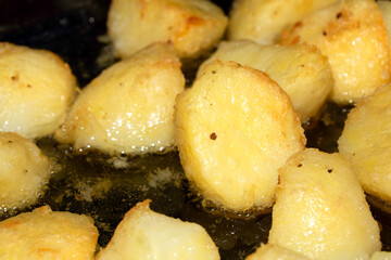Close up of delicious fresh roast potatoes cooking in fat oil close up