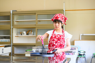 料理教室で調理を学ぶ小学生の女の子と料理の先生　教育と食育イメージ