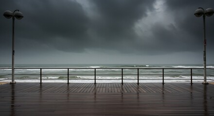 Naklejka premium an empty beachfront boardwalk. The sky is dark and brooding, with heavy rain falling. The ocean is a churning, gray mass.