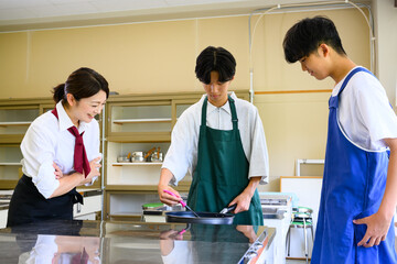 料理教室で学ぶ男子学生と女性講師　料理レッスン風景