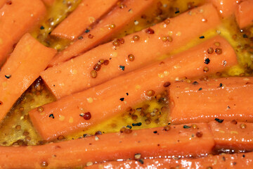 Close up of honey roasted carrots batons in oil cooking