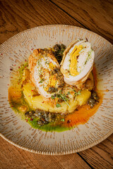 Delicious stuffed chicken breast plated with colorful sauces and fresh herbs on a wooden surface