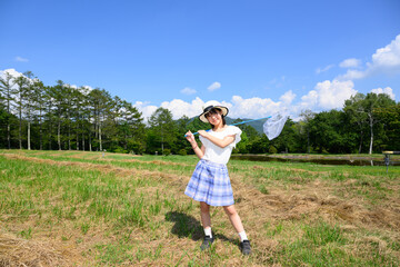 Obraz premium 青空の下で虫取りを楽しむ女の子