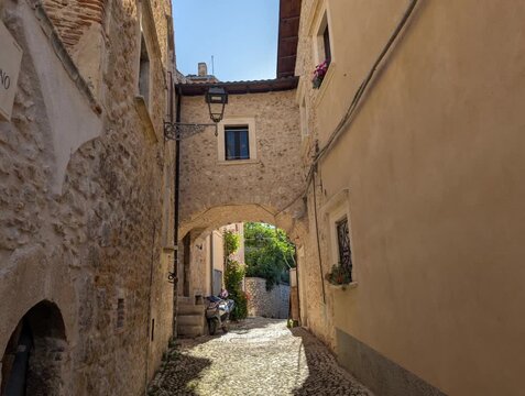Vicolo di un antico centro storico con arco sul passaggio, con edifici in pietra e mattoni che riflettono uno stile architettonico medievale.