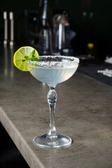 A vibrant margarita with lime garnish sits invitingly on a sleek bar