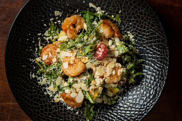 Savory shrimp salad combines vibrant greens, sliced almonds, and flavors in a chic black bowl