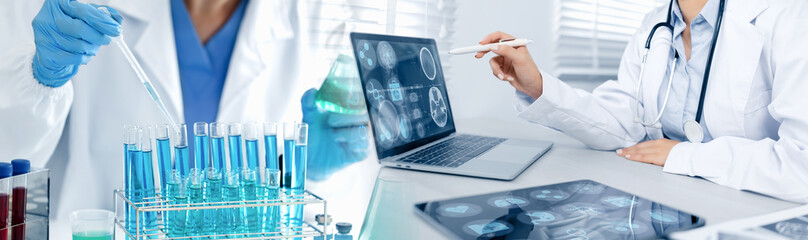 Fototapeta premium doctor working with examining x-ray on laptop and test tubes with liquid in laboratory, medical technology and scientist concept.