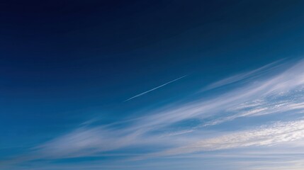 Photograph of a clear blue sky. the sky is a deep, rich shade of blue with a few wispy clouds scattered across it. the clouds are white and fluffy, and they appear to be floating in the air.