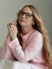 Young blondie attractive woman in eye glasses siting in studio. Business smart woman concept