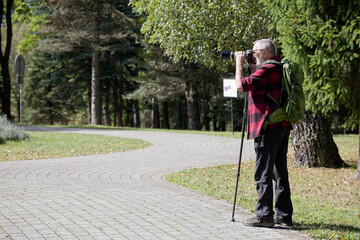 Senior professional photographer taking picture with monopod. Travel and outdoor photography.