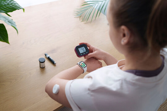Woman with diabetes synchronizing smart watch and glucometer at home