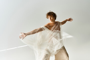 Dancer with curly hair expresses movement in a studio with a grey backdrop