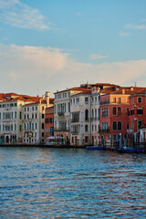 Historic colorful buildings along the Grand Canal in Venice, Italy at sunset with boats moored by water. Concept of travel, architecture and tourism