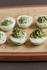 close up of green rotten deviled eggs served on a dark plate, spooky halloween party appetizer with creepy coloring and creamy filling