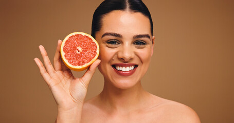 Happy woman, portrait or skincare with grapefruit for glowing skin on a studio background. Face, female person or model with smile or natural organic fruit for vitamin C or antioxidant on space