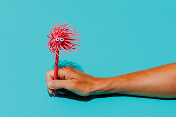 Hand holding pink novelty pen in playful mood against blue background