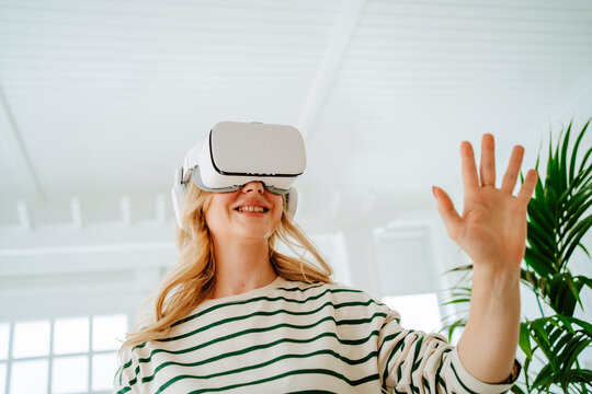 Happy woman playing games through VR glasses at home